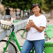 Female veteran holding phone leaning against bike